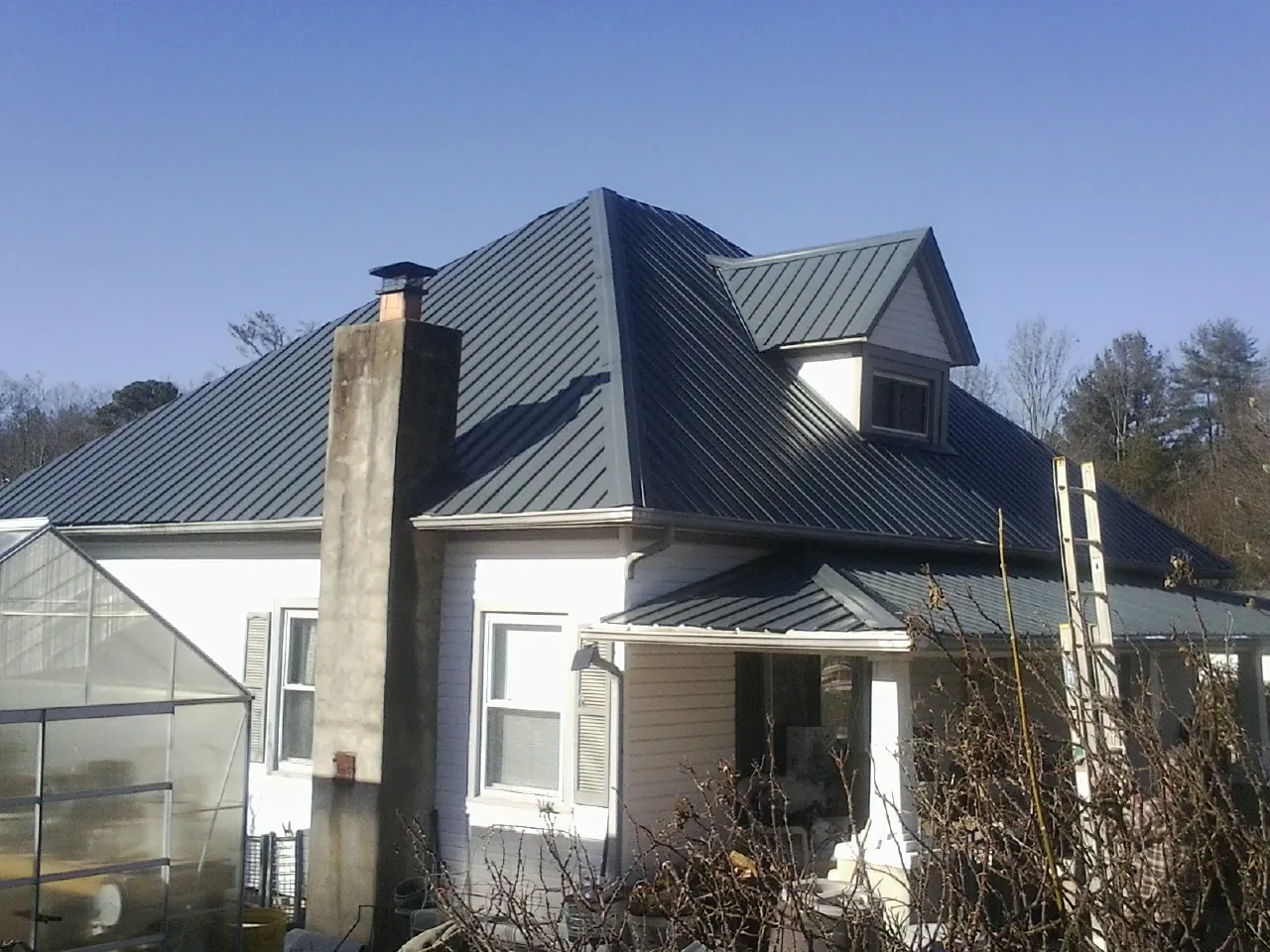 Dark blue standing seam metal roof on a white farmhouse with dormer — Slate & Tile Roof Repair by Roofing Brothers in Belfair