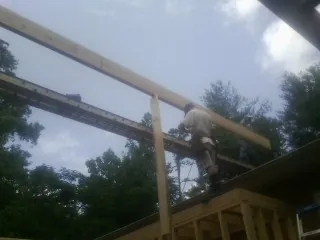Carpenter setting a ridge beam over a new addition frame — Ice Dam Removal by Roofing Brothers in Belfair
