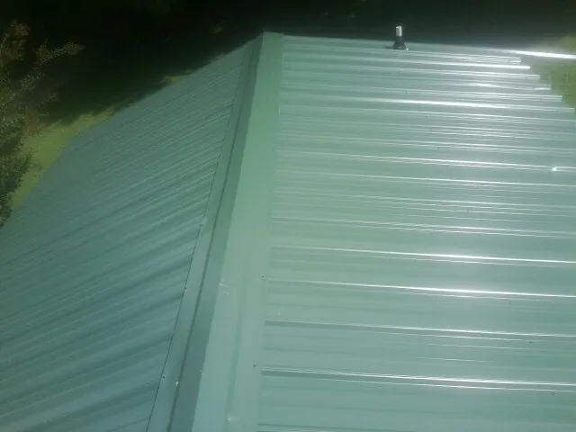 New green metal panels meeting at the ridge of a roof — Flat Roof Repair work by our crew in Belfair