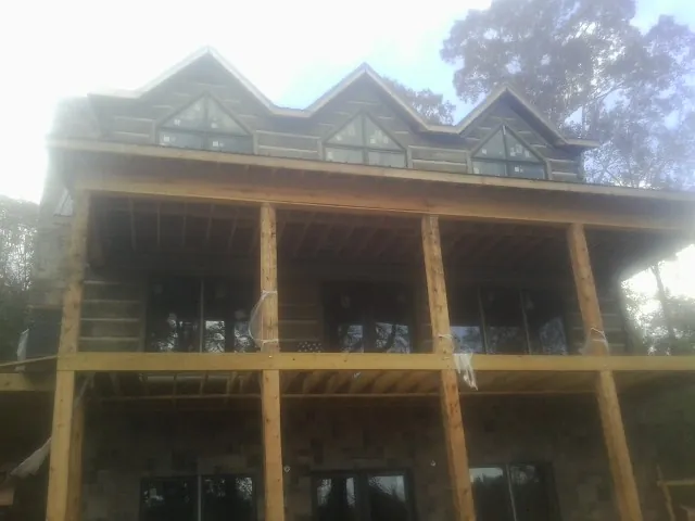 Dormers and porch framing on a large log home under construction — Roof Coating work by our crew in Belfair