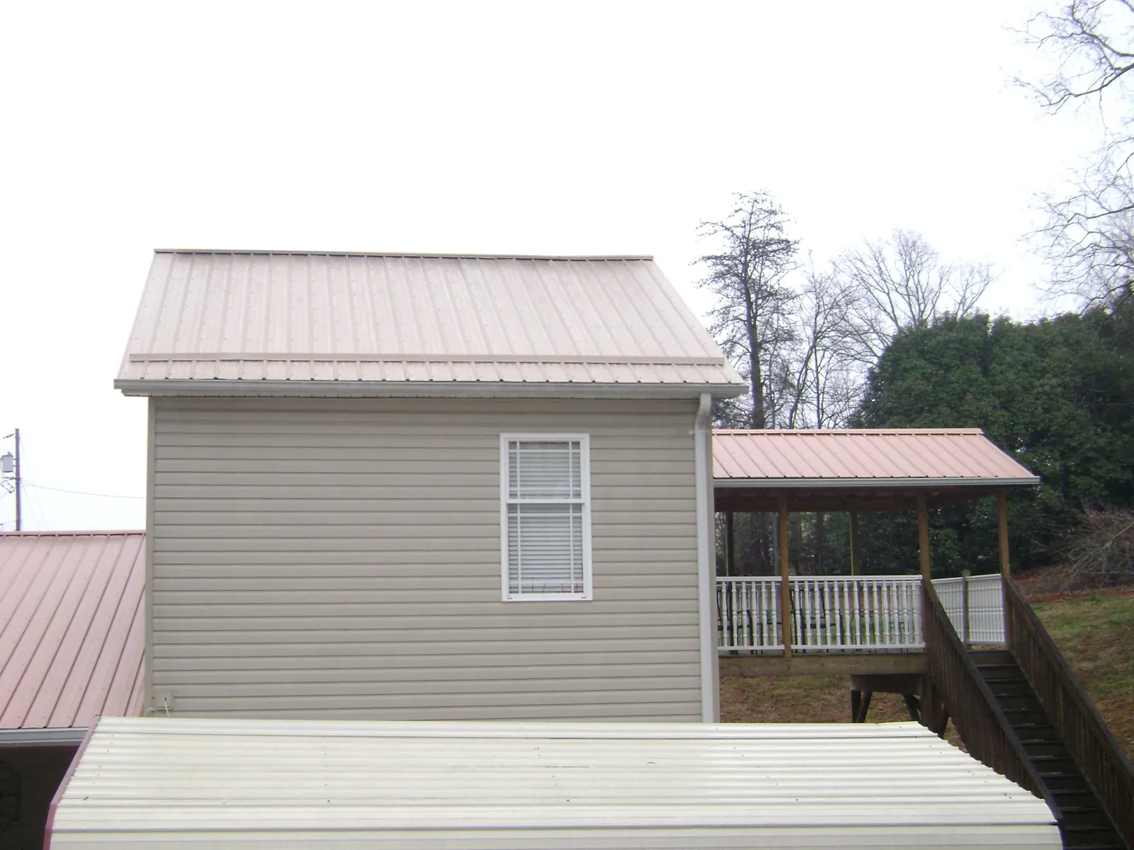 Tan metal roofs on a two story addition and attached porch, from a Roof Replacement job in Belfair