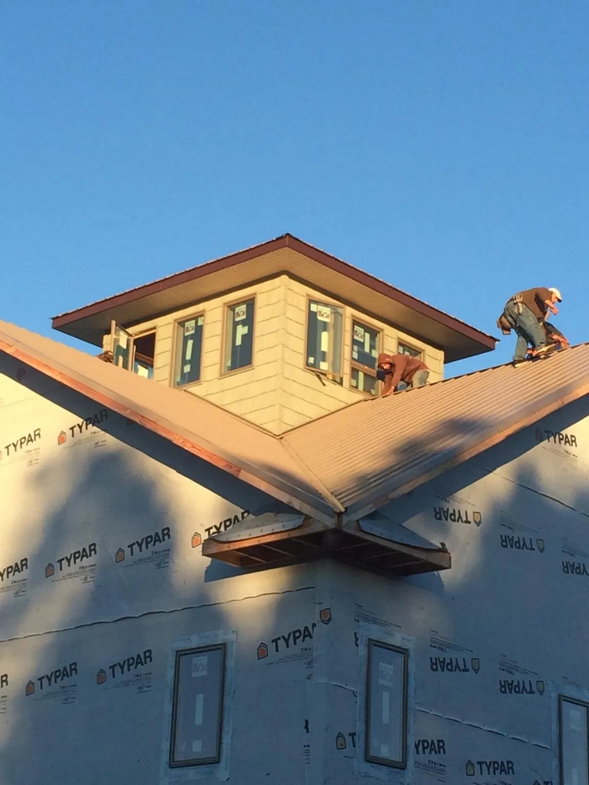 Roofers working around a rooftop cupola on a new metal roof at sunset — Roof Waterproofing in Belfair by Roofing Brothers